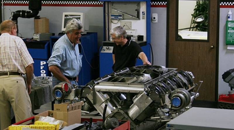 Looking it over Jay Leno, Gale Banks, and Bob Robe (Chief Designer) look over the tank engine that will be modified.