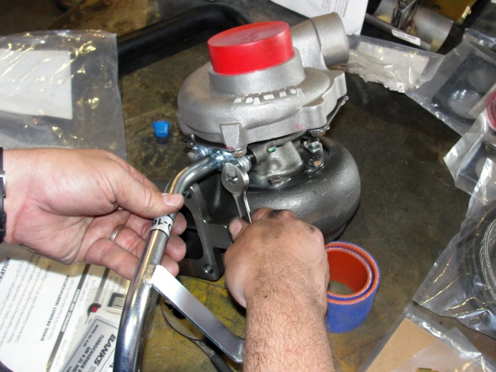 A drain tube used to connect the new lift pump spacer plate can now be mounted to the center bearing assembly of the turbo. (photo ref: hands, turbos w/ red caps)