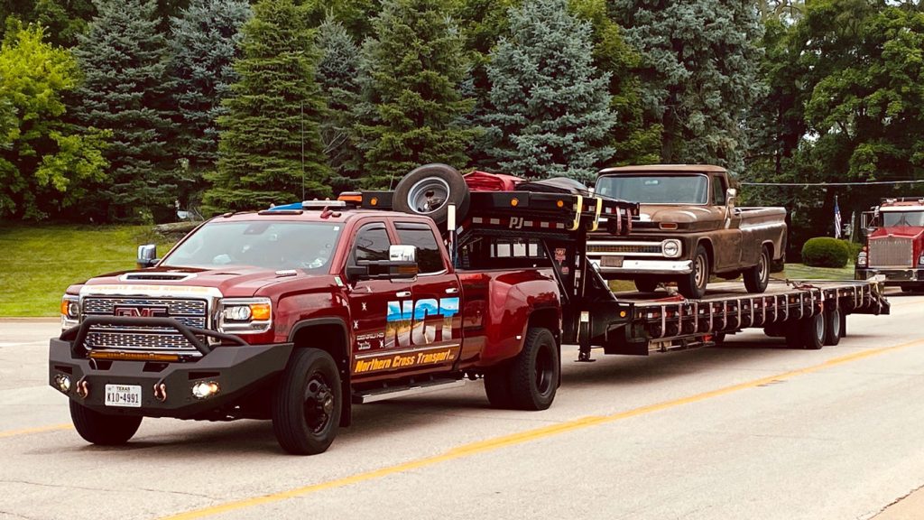 The Alaskan Duramax hauls a Chevy on a flatbed.