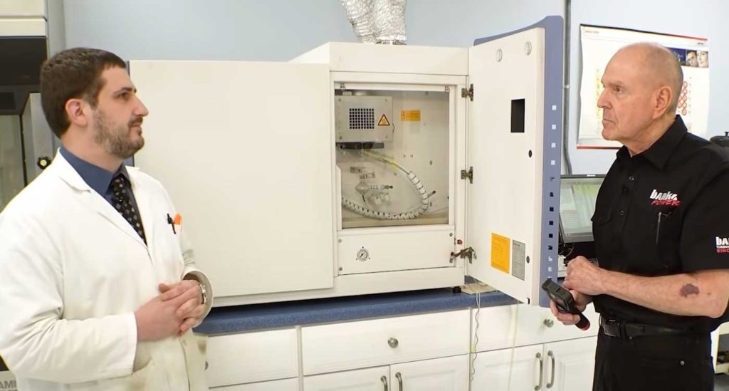 Gale and a motor oil scientist stand in front of one of the test apparatuses.